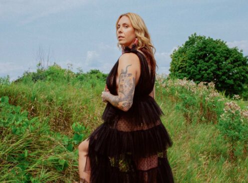 A woman wearing a black dress and posing outside