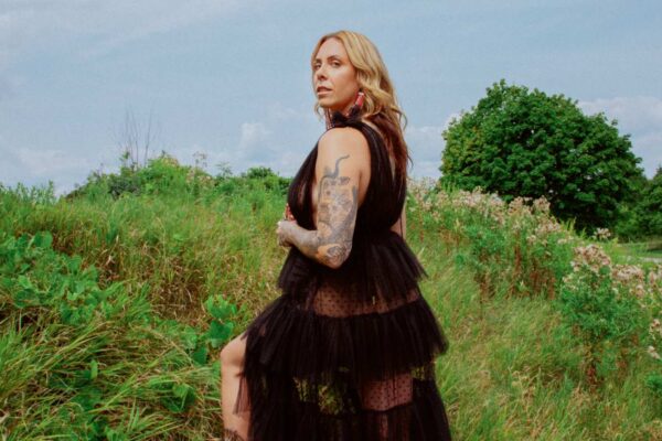 A woman wearing a black dress and posing outside