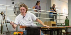 Artist blowing glass in studio
