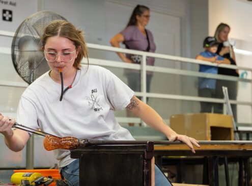 Artist blowing glass in studio