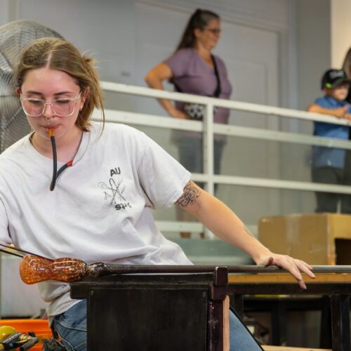 Artist blowing glass in studio