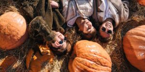 Three women lying on the ground next to pumpkins