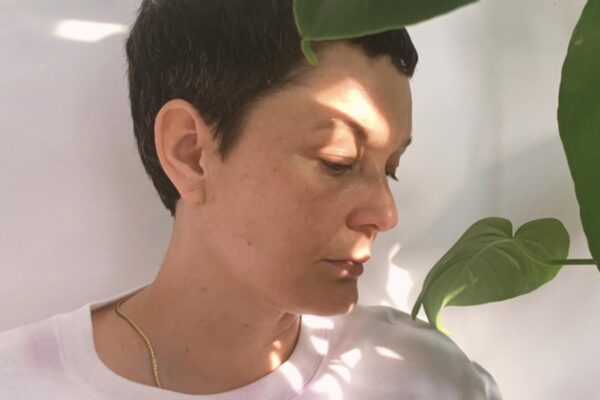 A close-up image of a woman posing by a plant