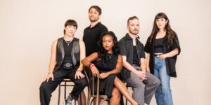 A group of musicians wearing black posing for the camera