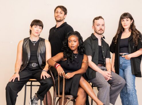 A group of musicians wearing black posing for the camera