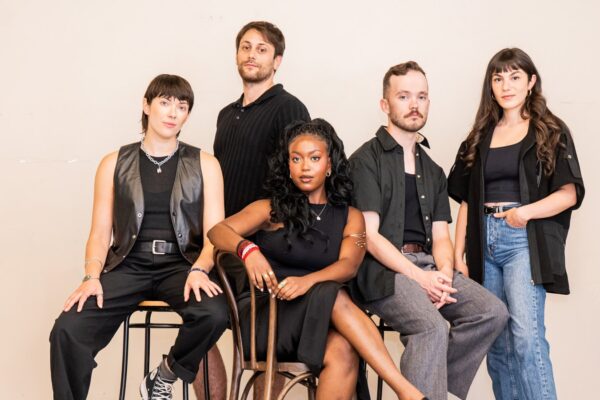 A group of musicians wearing black posing for the camera