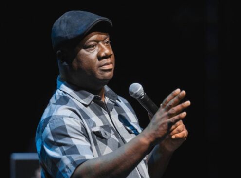 A comedian on stage holding a mic