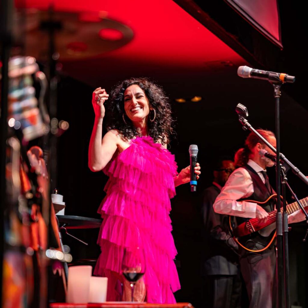 A woman wearing a bright pink dress on stage performing