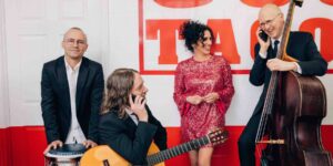 A band smiling and posing against a wall