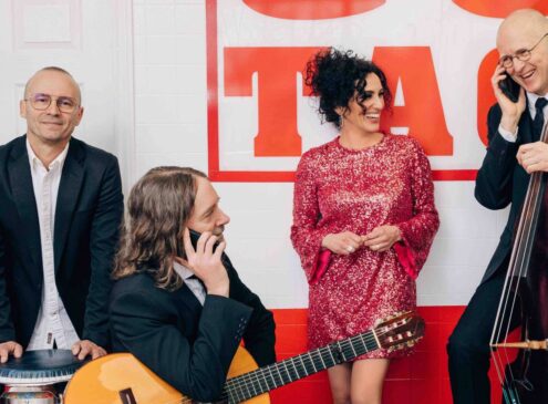 A band smiling and posing against a wall