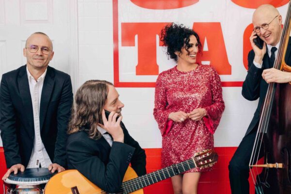 A band smiling and posing against a wall