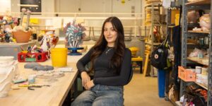 A woman wearing a black shirt posing for the camera sitting in a studio