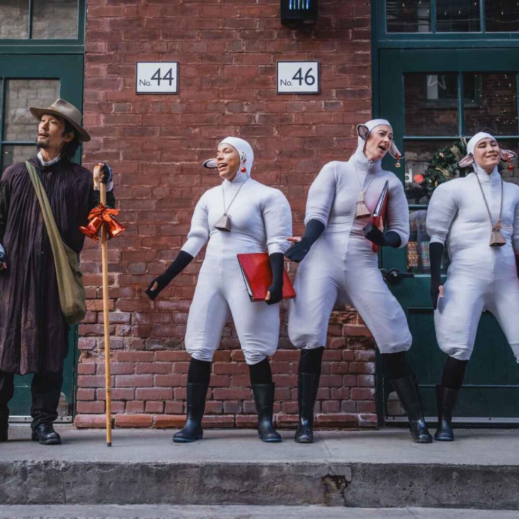 A group of sheep performers and a shepherd singing outdoors