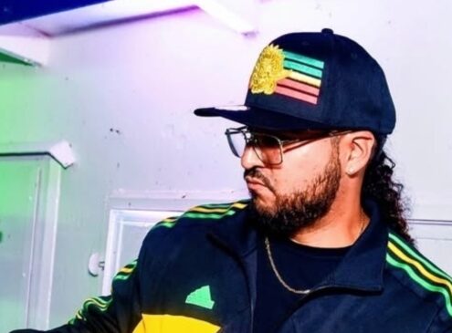 A man wearing a baseball cap spinning music at a DJ booth