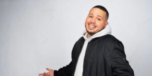 A man wearing a hoodie and jacket posing for the camera