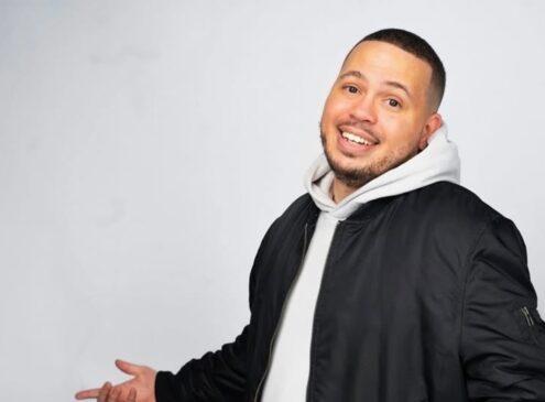 A man wearing a hoodie and jacket posing for the camera