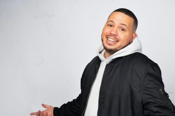 A man wearing a hoodie and jacket posing for the camera