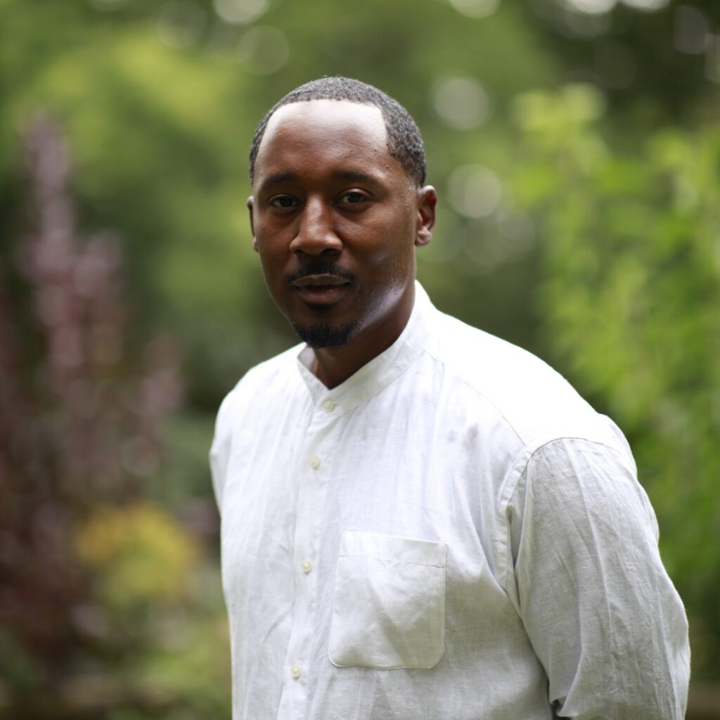 A man wearing a white shirt outdoors posing for the camera