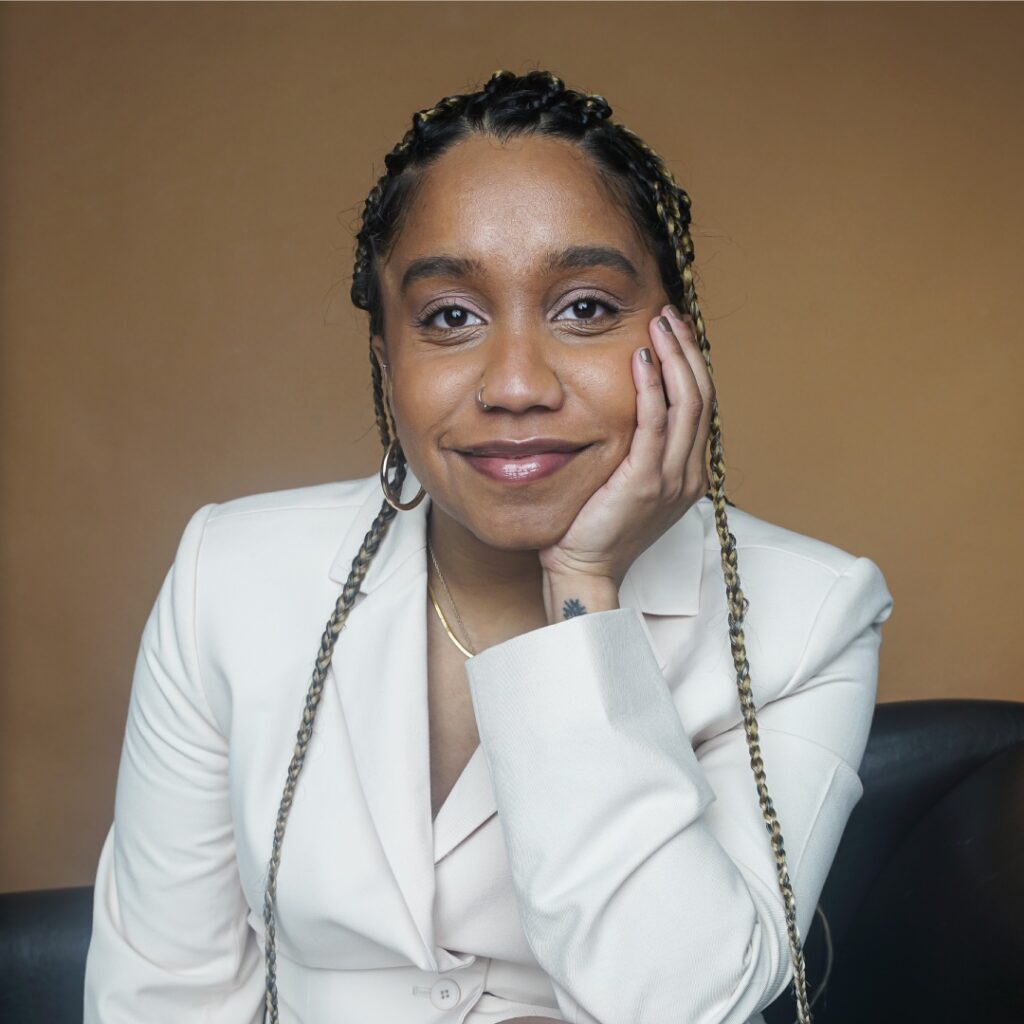 A woman wearing a white blazer smiling for the camera