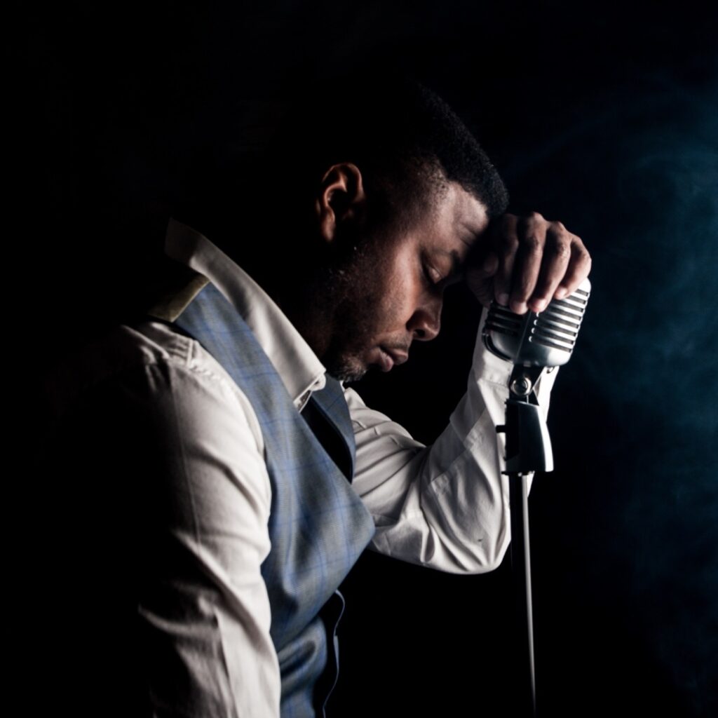 A man holding a mic against a dark background
