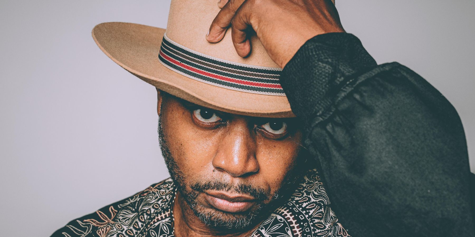 A close-up of a man wearing a hat posing for the camera
