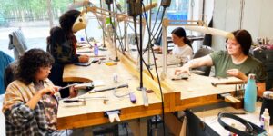 A group of artists working in a metal studio