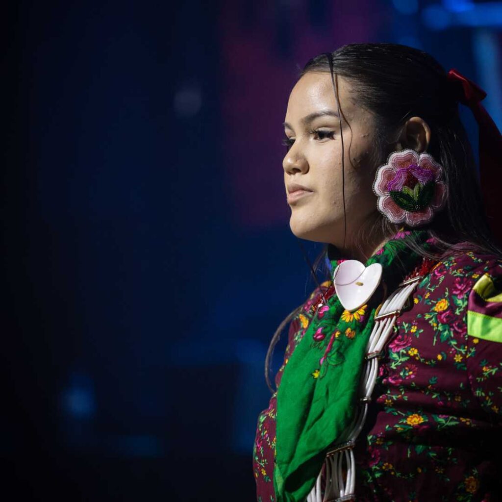 A woman wearing colourful attire against a dark background