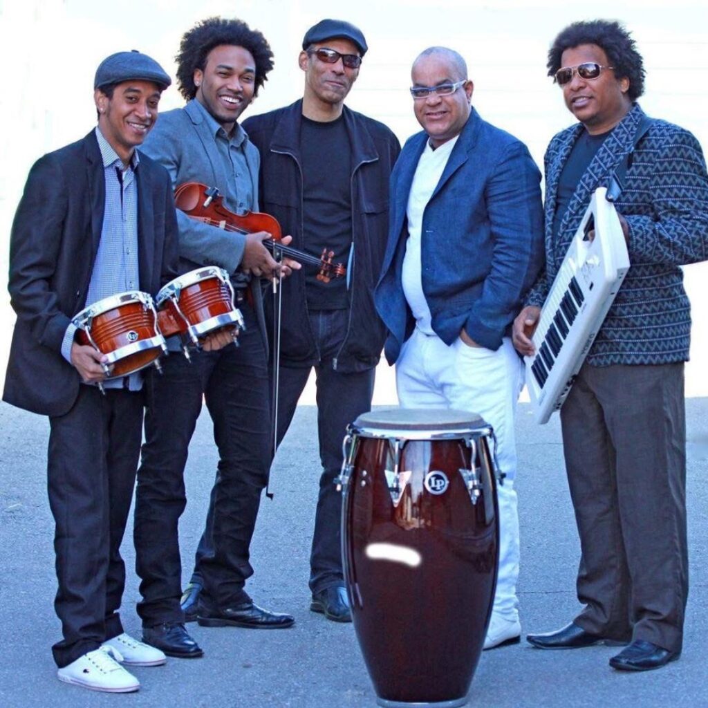A group of musicians standing with musical instruments and posing for the camera