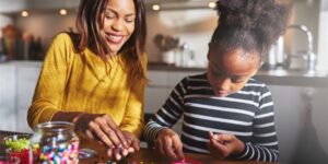 A mom and her daughter playing with arts and crafts at a table