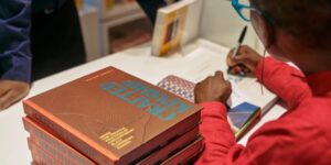 An up-close shot of an author signing a book while sitting at a table