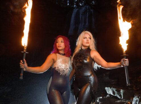Two women wearing black and holding fire torches