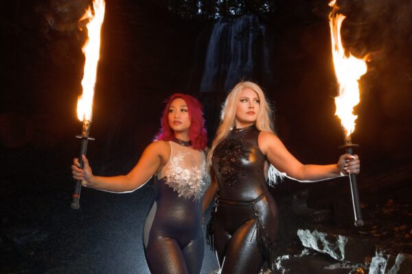 Two women wearing black and holding fire torches