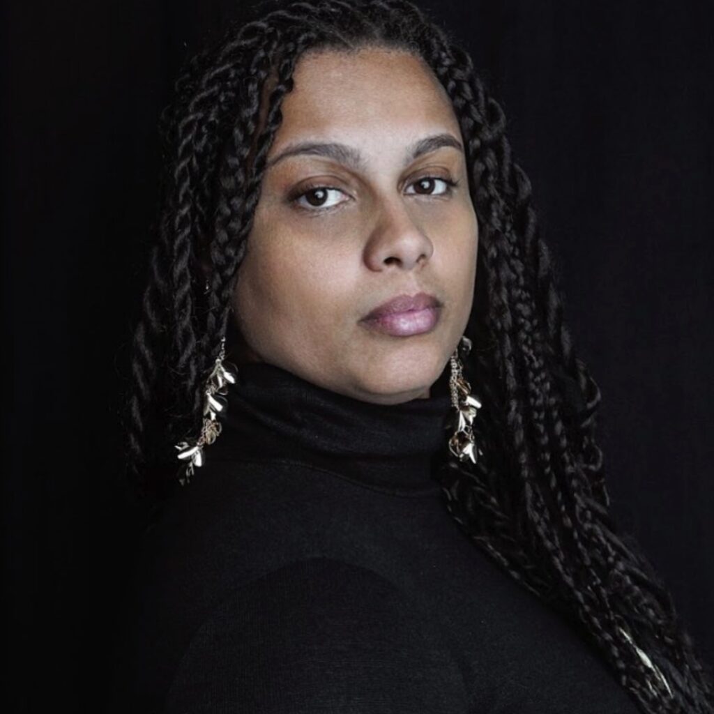 A woman wearing a black shirt against a dark background posing for the camera