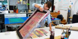 A woman screen printing in a studio