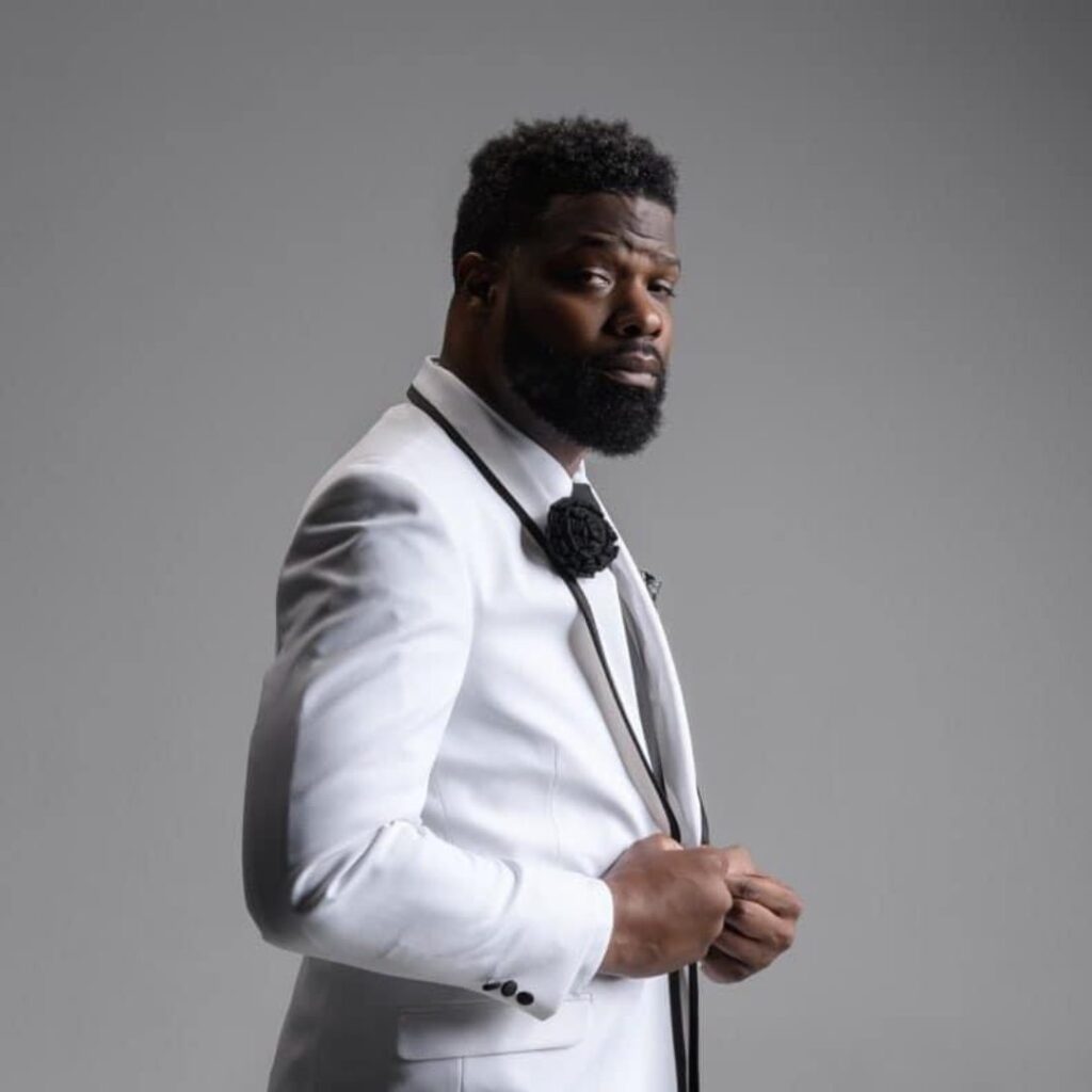 A man wearing a white blazer and posing for the camera