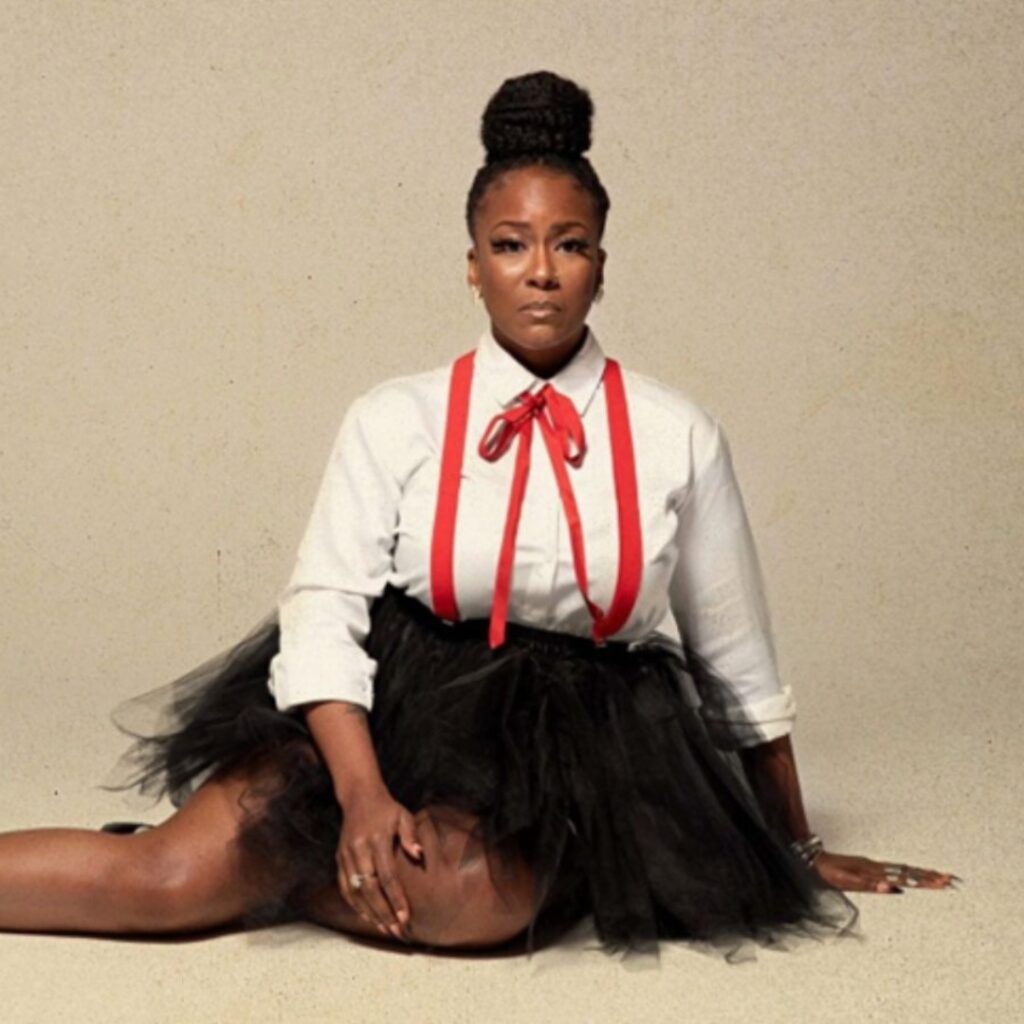 A person wearing a black skit sitting on the ground posing for the camera