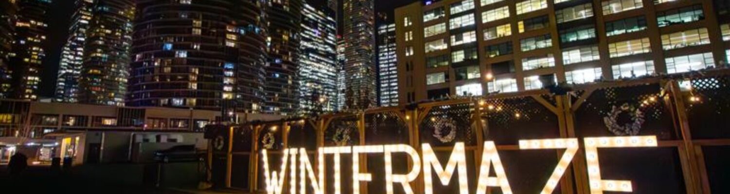 An outdoor maze at night with a lighted sign Winter Maze