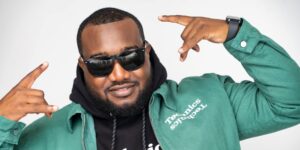 A man wearing a green jacket and sunglasses posing for the camera