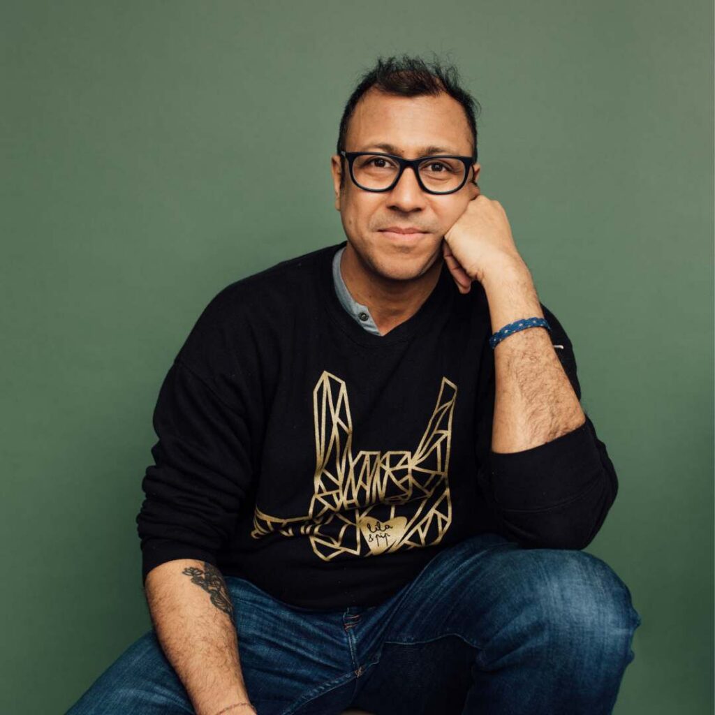 A man posing against a dark green background