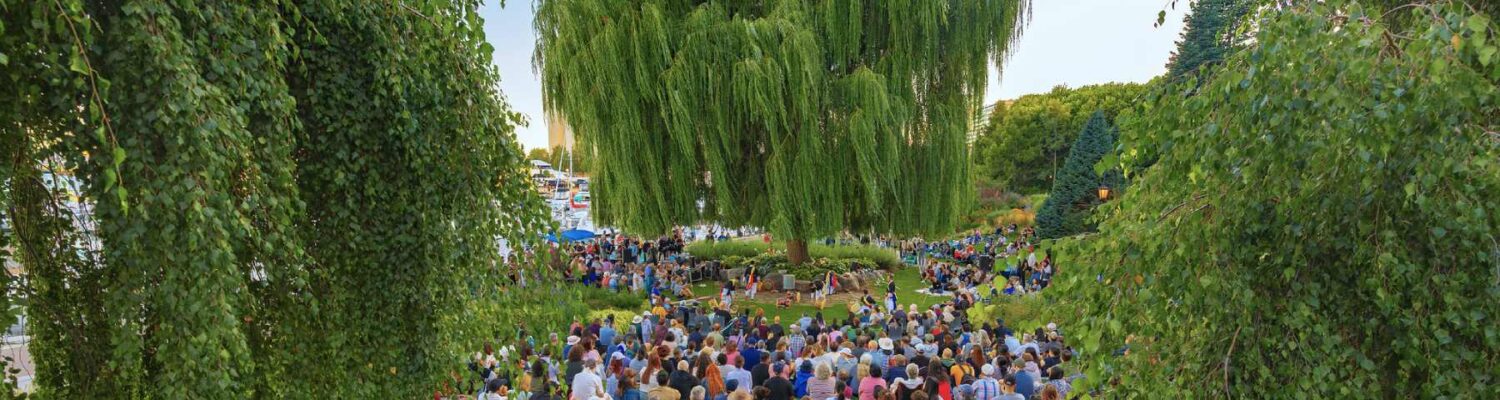 A crowd listening to an outdoor music concert in a garden