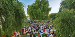 A crowd listening to an outdoor music concert in a garden