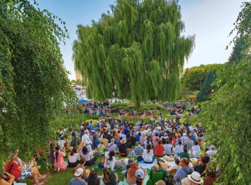 A crowd listening to an outdoor music concert in a garden