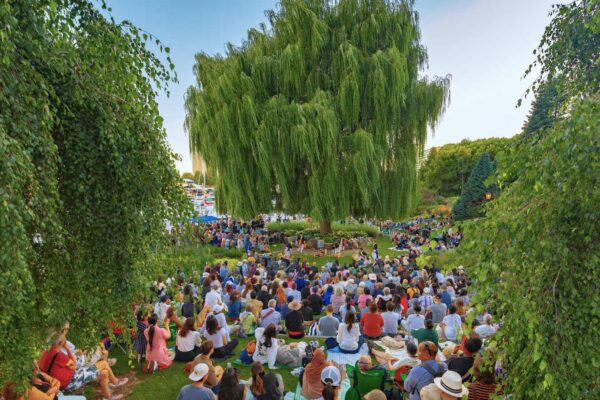 A crowd listening to an outdoor music concert in a garden
