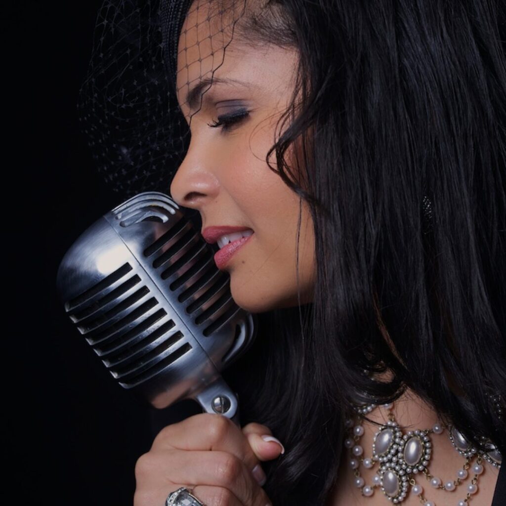 A close-up image of a singer holding a mic against a black background
