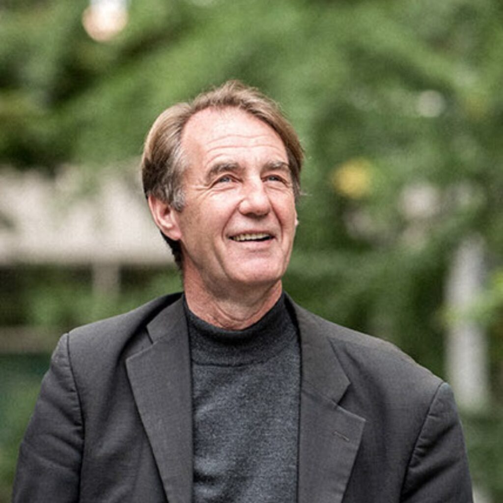 A man wearing a dark blazer looking up into the distance