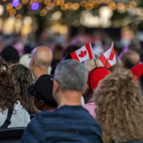 An outdoor crowd holding a Canadian flag