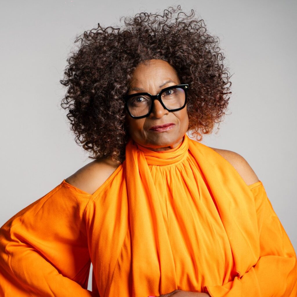 A woman wearing a bright orange shirt and glasses