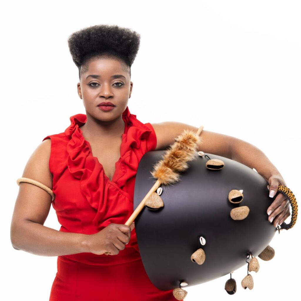 A woman wearing a bright red dress posing with a black musical instrument