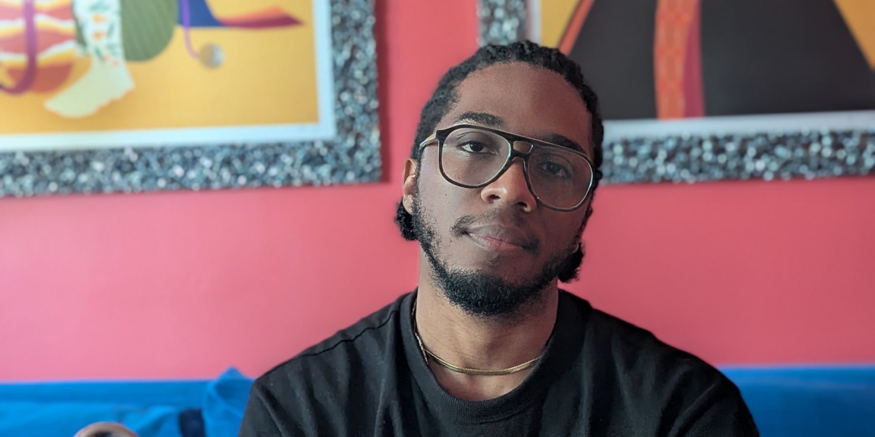 A man sitting on a blue couch posing for the camera