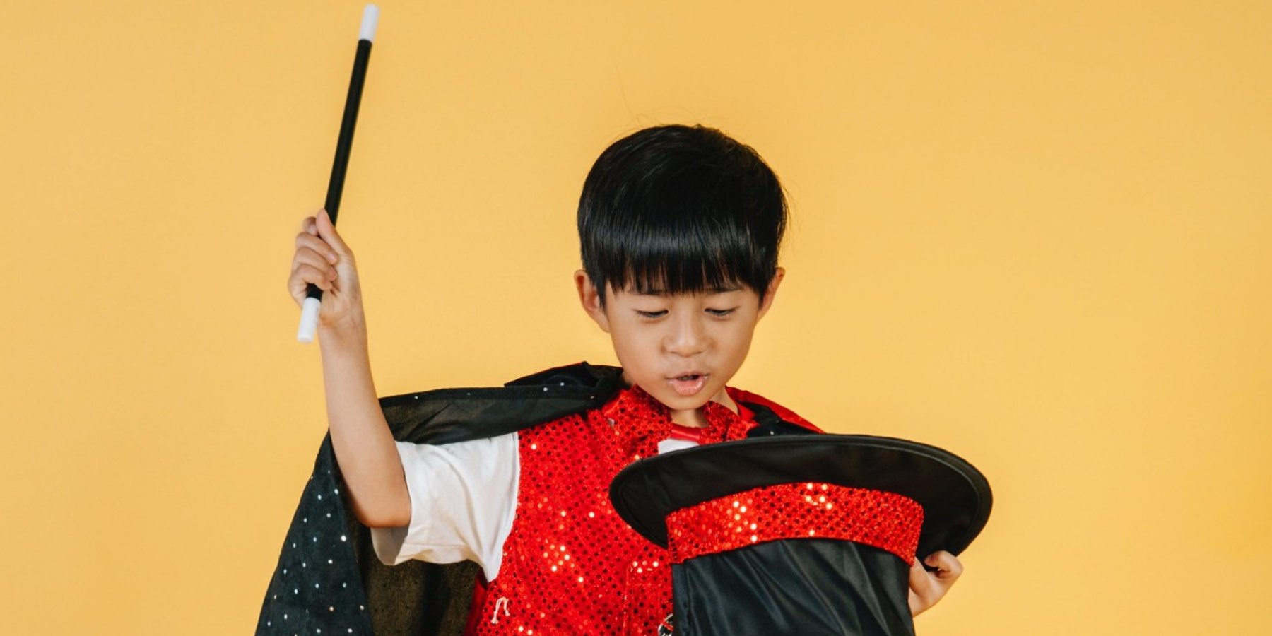 Young child wearing a cape and holding a magic wand